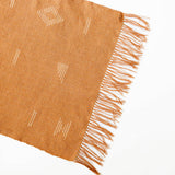 Fringed terracotta cotton woven table runner with white geometric designs on a white backgrou d