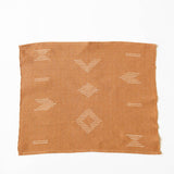 Terracotta napkin used as a placemat with white geometric designs on white background