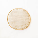 A round beige Handwoven Cotton Tortilla Warmer sits elegantly on a table, showcasing its natural, earthy tones and intricate handwoven texture. Made from 100% cotton, this eco-friendly warmer adds a rustic, artisan touch to any meal while keeping tortillas warm.