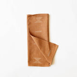 Folded terracotta colored cotton napkin on white background