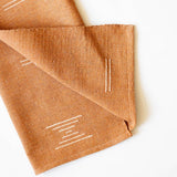 Closeup of terracotta napkin with white geometric Mexican designs