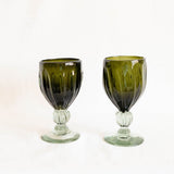 Two olive green wine glass goblets on a white background