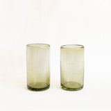Two olive green glass tumblers on a white background