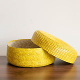side view of a yellow round Handwoven Natural Palm Tortilla Warming Basket (tortillero) with Lid slightly ajar