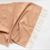 Beige cotton hand towel with geometric patterns and fringes on a white background