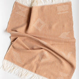Beige brown hand towel with white geometric patterns and fringes on a white background