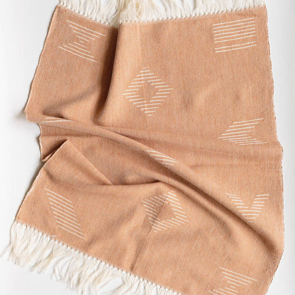 Beige brown hand towel with white geometric patterns and fringes on a white background