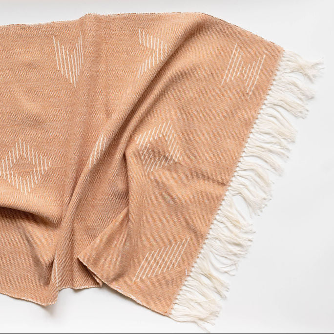Beige cotton hand towel with geometric patterns and fringes on a white background