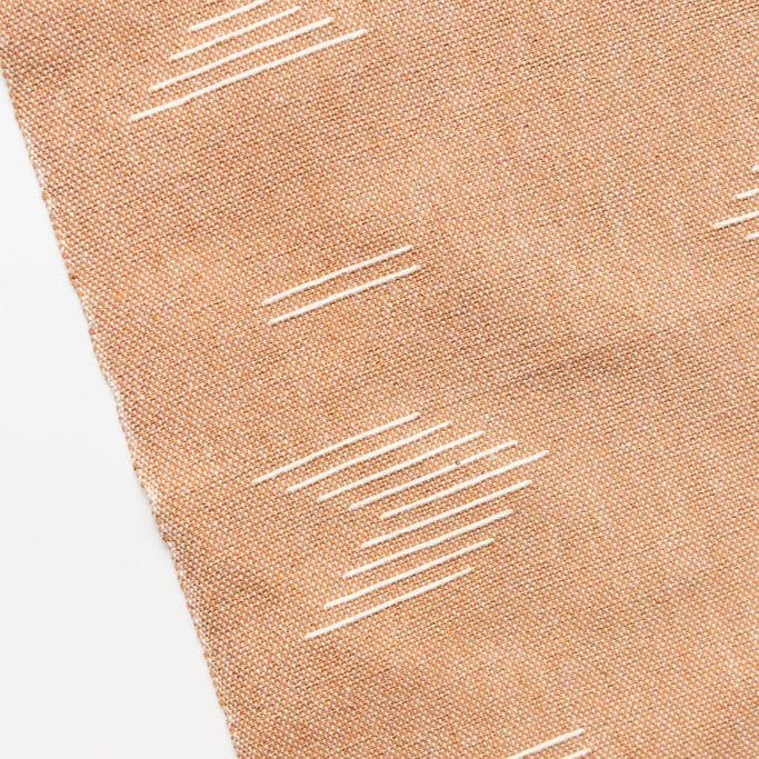 Brown cotton hand towel with white geometric patterns on a white background
