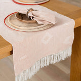 Cotton Table Runner styled with plates, palm placemats and napkins with napkin rings. 