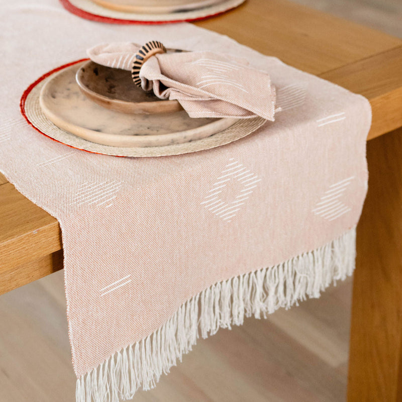 Cotton Table Runner styled with plates, palm placemats and napkins with napkin rings. 