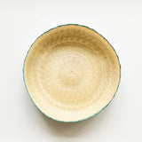 Top view of a palm woven tortilla warmer basket with emerald green on outside and natural on the inside on a white background