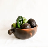 Ceramic bowl with avocados and a pepper on a white background