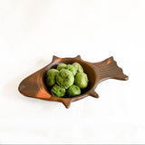 Fish-shaped bowl with green tomatillos on a white background