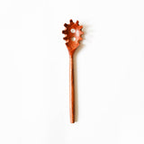 Wooden spaghetti spoon with a unique design on a white background.