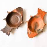 Two ceramic dishes shaped like a shell and a fish on a white background