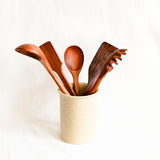 Set of wooden utensils in a beige container on a white background