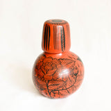 Terracotta Ceramic carafe with black floral patterns on a white background