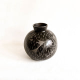 Black ceramic vase with engraved design on a white background