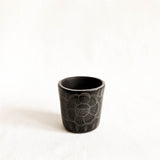 Black ceramic cup with floral design on a white background