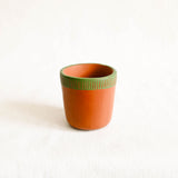 Ceramic cup with green textured rim on a white background