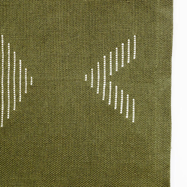 Closeup of a andwoven forest green cotton dinner napkin and placemat featuring beige geometric designs