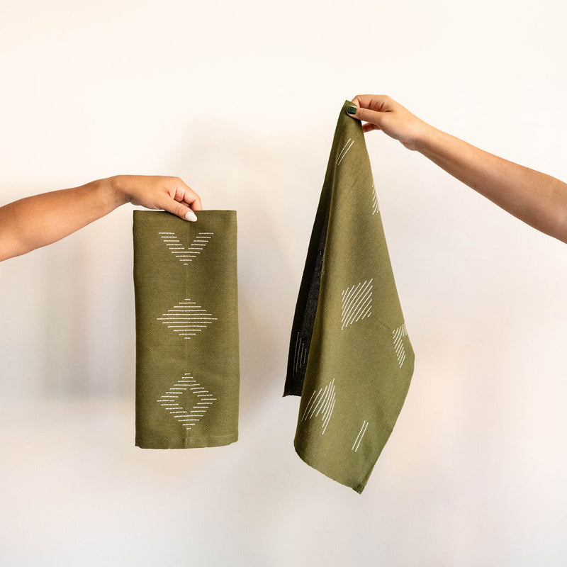 Handwoven forest green cotton dinner napkin and placemat featuring beige geometric designs
