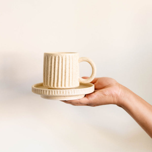 Vanilla Creme Mexican Ceramic Mug held by the handle with a soft, off-white finish and a smooth, matte texture. 