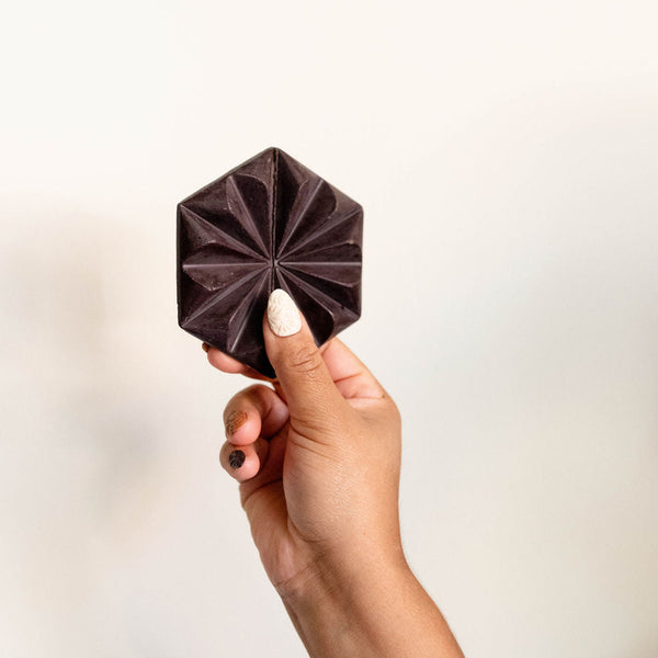 handcrafted, hexagonal Mexican hot chocolate tablet of single-origin chocolate. The tablet features a decorative floral-like pattern, showcasing artisanal Mexican chocolate craftsmanship.