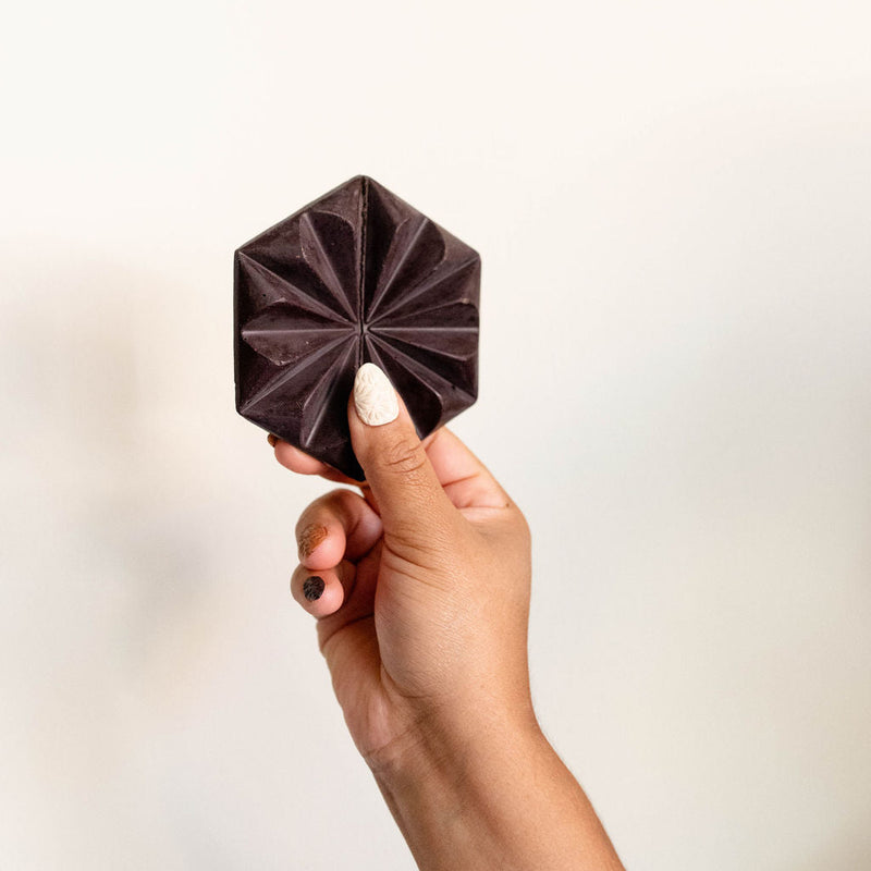 Hand holding Hijita Mexican Chocolate bar with a star-shaped design against a light background