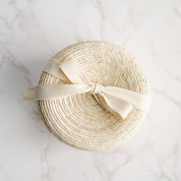 Keepsake gift basket with a lid handcrafted with sustainable palm. Basket is tied with a bow