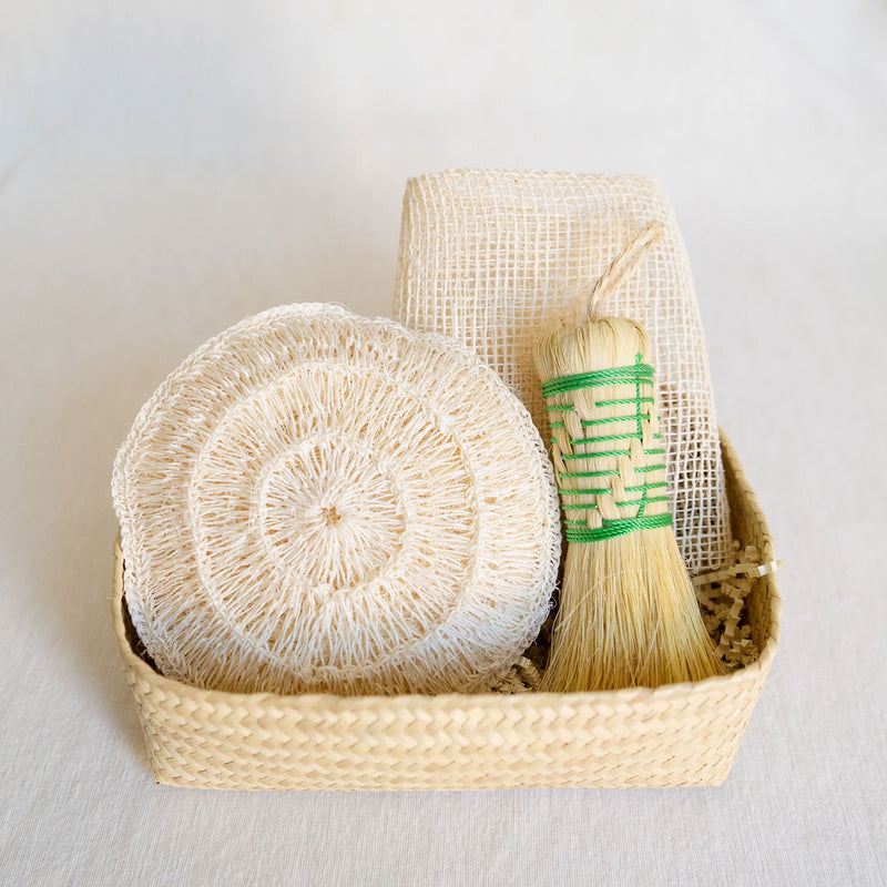 Agave Rituals Gift Basket featuring an assortment of agave-based self-care items, including a hand dish brush (Escobeta) available in green, an Ayate washcloth, and a large agave body sponge, all neatly arranged in a handwoven palm gift basket.