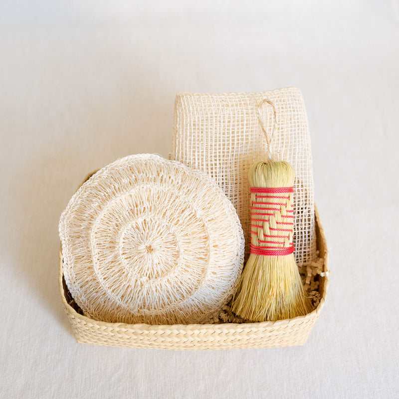 Agave Rituals Gift Basket featuring an assortment of agave-based self-care items, including a hand dish brush (Escobeta) available in pink, an Ayate washcloth, and a large agave body sponge, all neatly arranged in a handwoven palm gift basket.