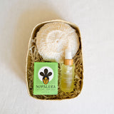 A beautifully curated gift set featuring a Nopalera Planta Futura Soap Bar, an exfoliating Agave Body Sponge, and Sanara Skincare's Chilean Rosehip Seed Body Oil, all elegantly arranged in a handcrafted palm gift basket. This collection is perfect for a luxurious self-care ritual, blending artisanal Mexican products with nourishing ingredients.