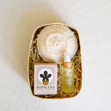 A beautifully curated gift set featuring a Nopalera Flor De Mayo Soap Bar, an exfoliating Agave Body Sponge, and Sanara Skincare's Chilean Rosehip Seed Body Oil, all elegantly arranged in a handcrafted palm gift basket. This collection is perfect for a luxurious self-care ritual, blending artisanal Mexican products with nourishing ingredients.