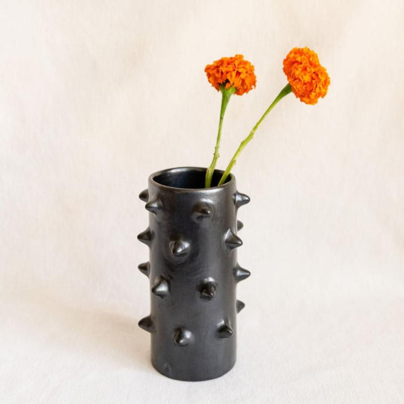 Barro Negro Black Clay Decorative Vase featuring a modern spiked design inspired by the pochote tree, a native tree with sharp thorns. Pictured with two marigolds.