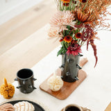 Handcrafted Spiked Black Clay Vase made from authentic Mexican black clay (barro negro), featuring a bold, modern spiked design. Perfect for contemporary home decor or as a unique artisanal statement piece. Pictured in a table setting with flowers.