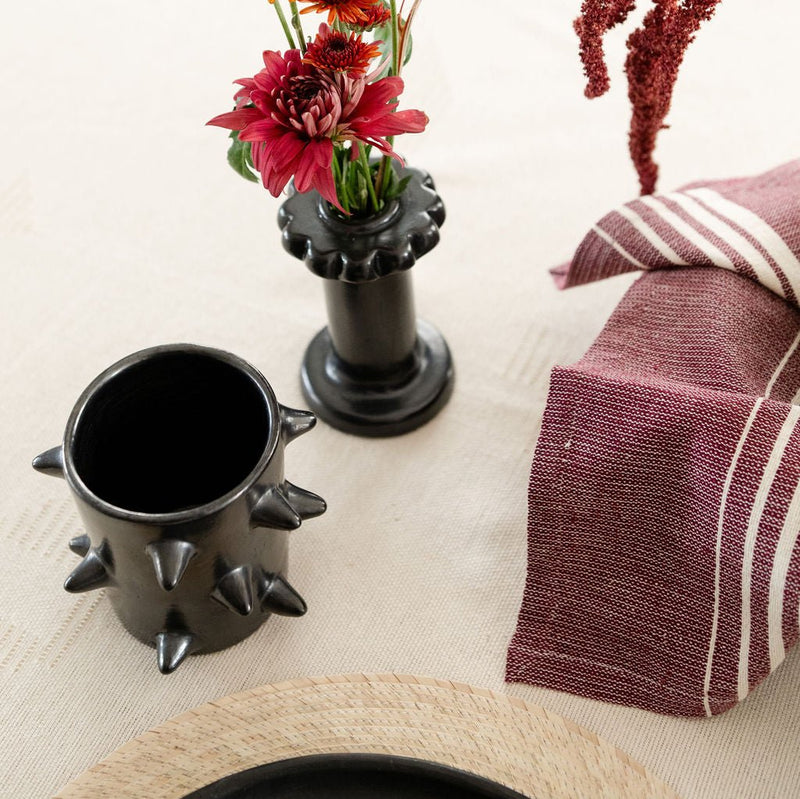 Handcrafted Spiked Black Clay Cup made from authentic Mexican black clay (barro negro), featuring a bold spiked design with a smooth black metallic finish. Perfect for modern drinkware or as a unique artisanal decor piece. Pictured in a table setting.