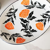 Enamel Peltre serving tray in white with delicate orange floral accents inspired by the cempasúchil flower. The tray features a smooth, glossy finish and raised edges for easy carrying, perfect for serving snacks, or as a decorative centerpiece.