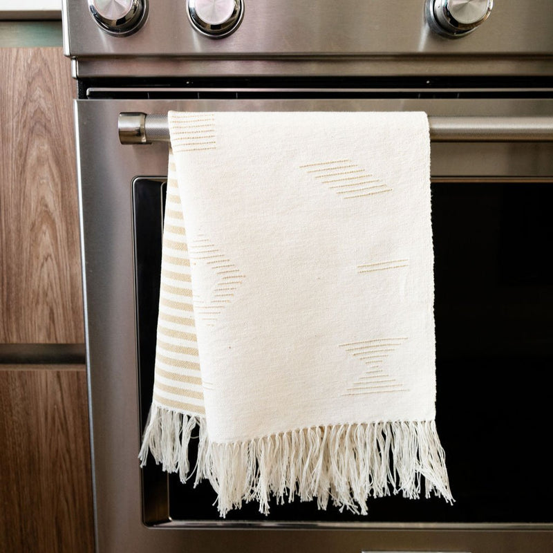 Handwoven Cotton Tea Towel and Hand Towel in gold and beige with geometric lines hanging from a stove