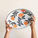 Enamel Peltre serving tray in white with delicate orange floral accents inspired by the cempasúchil flower. The tray features a smooth, glossy finish and raised edges for easy carrying, perfect for serving snacks, or as a decorative centerpiece.