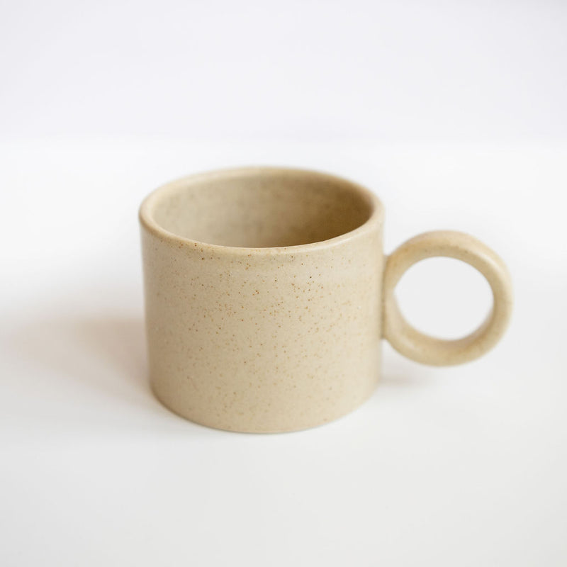 Vainilla Creme Ceramic Mug with a soft, off-white finish and a smooth, matte texture. The mug features a simple, elegant design with a comfortable handle, perfect for enjoying a cozy cup of coffee or tea. The neutral tone complements any kitchen or table setting.