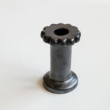 A handcrafted black clay holder with a scalloped top, featuring a smooth, metallic finish. It has a cylindrical body and a sturdy circular base, designed for dual use as a dried flower vase or candle holder.