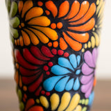 Closeup of hand-painted Talavera rainbow designs on a black ceramic tumbler