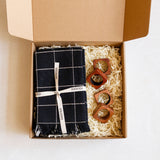 Gift Box containing a black and white checkered napkins with a white ribbon and 4 wooden napkin rings.