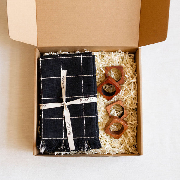 Gift Box containing a black and white checkered napkins with a white ribbon and 4 wooden napkin rings.