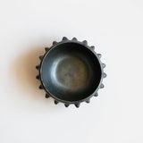 Black ceramic clay (barro negro) bowl with pointed rim on a white background