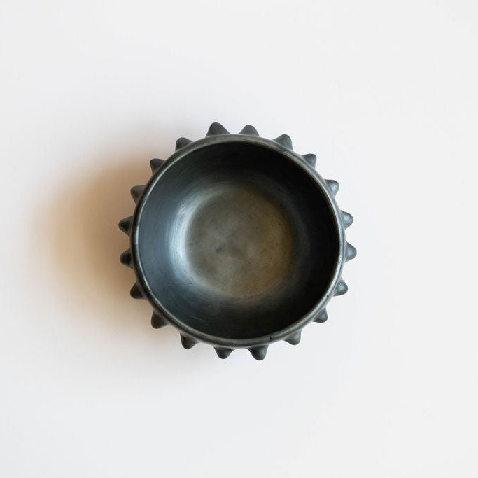 Black ceramic clay (barro negro) bowl with pointed rim on a white background