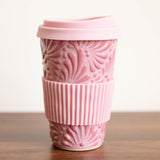 Pink Talavera ceramic tumbler with sleeve on a wooden surface with a white background