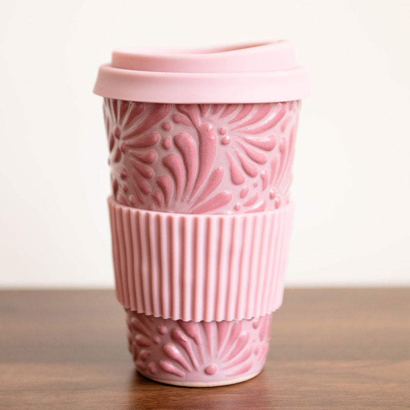Pink Talavera ceramic tumbler with sleeve on a wooden surface with a white background